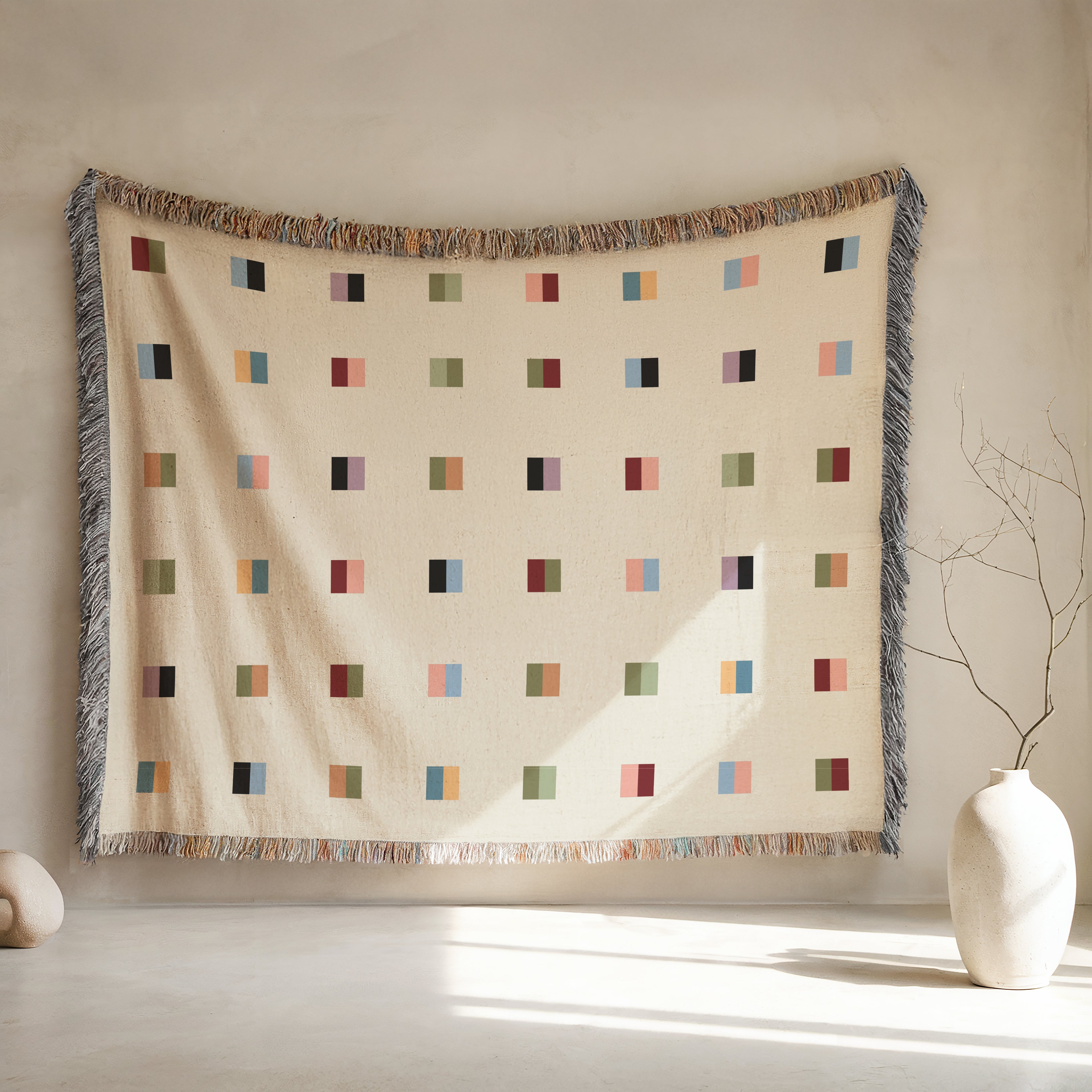 A cream-colored woven blanket with a Modern geometric split squares pattern of small multicolored squares and fringe edges. Scandinavia Design style for contemporary home decor.