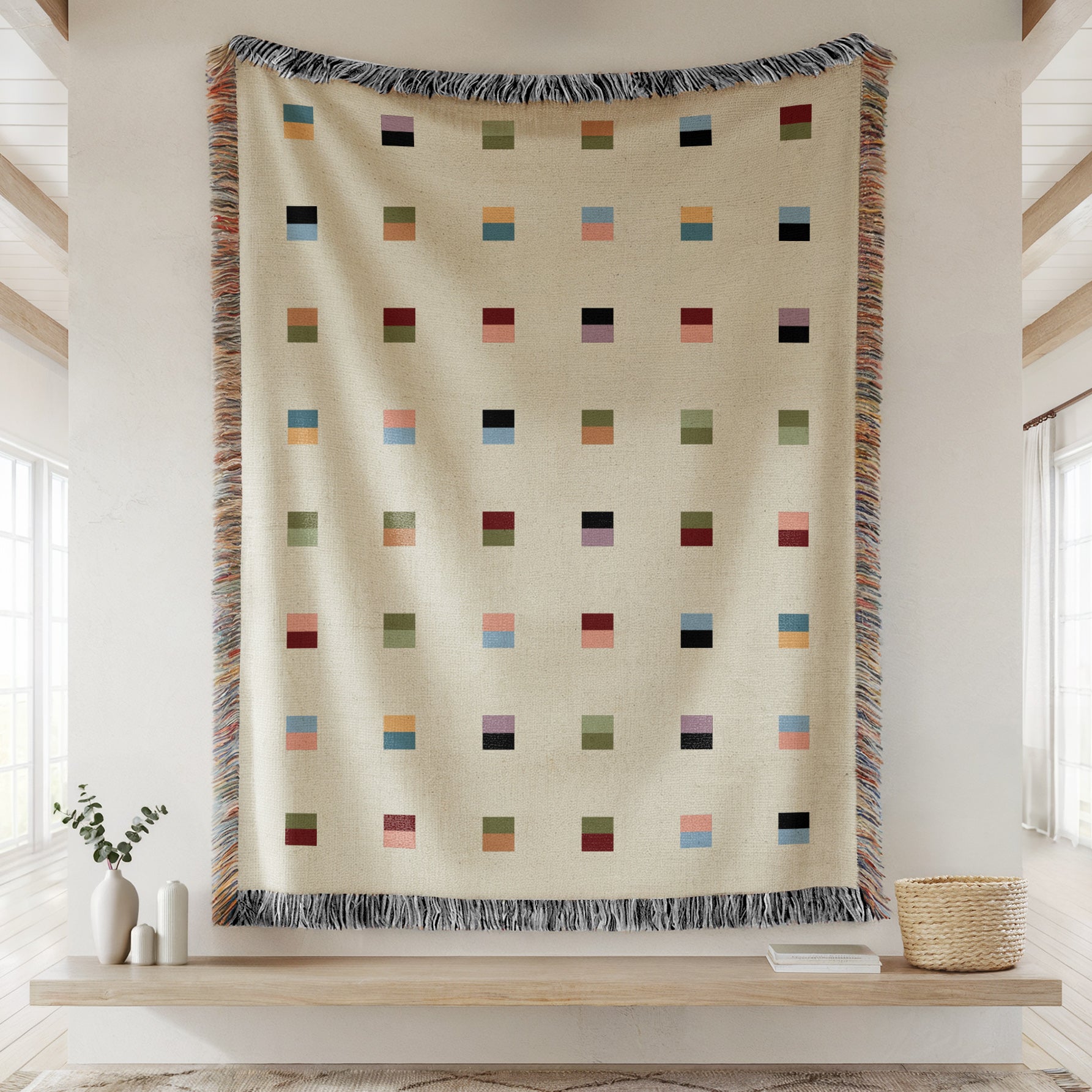 A cream-colored woven blanket with a Modern geometric split squares pattern of small multicolored squares and fringe edges. Scandinavia Design style for contemporary home decor.